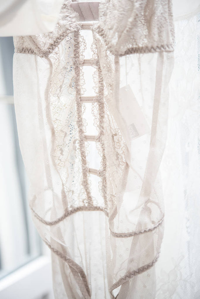 Элегантное кружевное белье на вешалке в подсветке, кружевные детали одежды
 - Фото, изображение