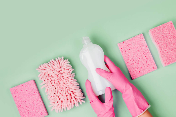 hands in pink rubber gloves holding bottle of cleanser with microfiber cloth and sponges - Foto, immagini