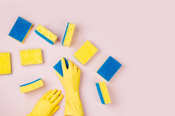 hands in rubber gloves with sponges on pink background - Foto, Bild