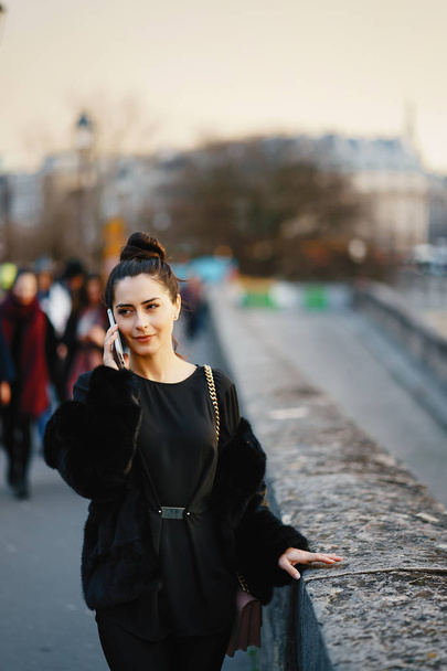 жінка за допомогою свого мобільного телефону під час прогулянки через Париж - Фото, зображення
