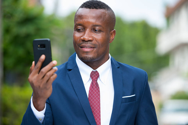 Young African businessman with mobile phone outdoors - Fotó, kép