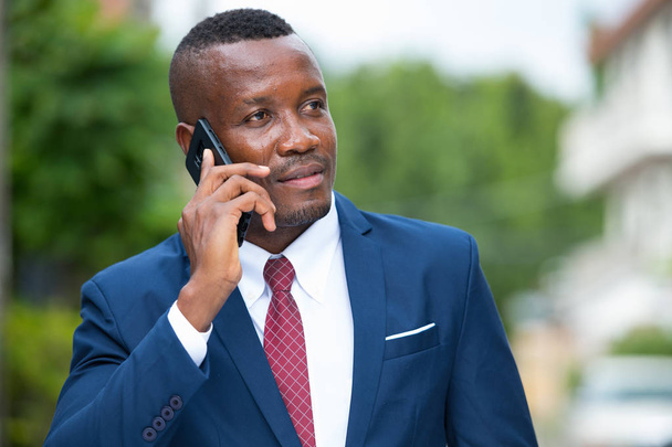 Nuori afrikkalainen liikemies matkapuhelimen kanssa ulkona
 - Valokuva, kuva