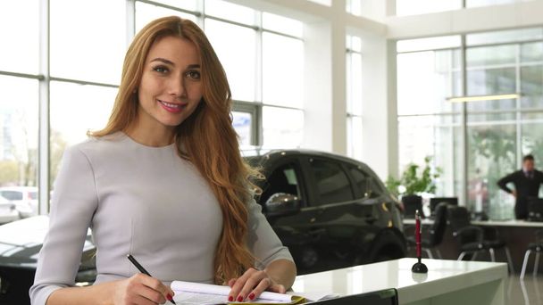 Шикарная женщина покупает новую машину в салоне, улыбаясь в камеру
 - Фото, изображение