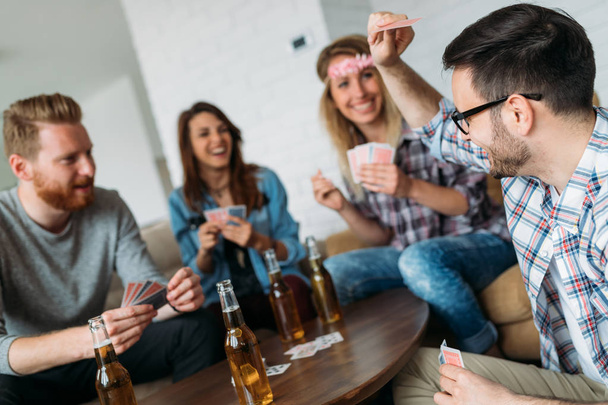 Happy group of smiling friends playing cards and drinking - Photo, image