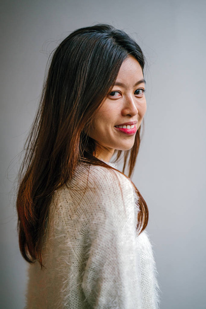 stylish and fashionable young Chinese Asian woman posing. She is wearing a beautiful white sweater - Photo, image