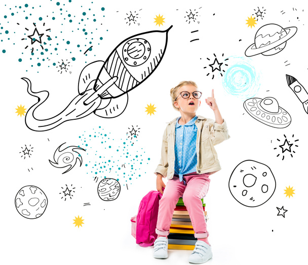 écolier excité pointant vers le haut et ayant l'idée tout en étant assis sur une pile de livres avec sac à dos isolé sur blanc avec univers fantastique, vaisseaux spatiaux et planètes
 - Photo, image