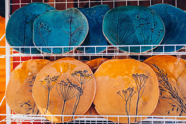Suvenýry s keramickými deskami. Ukázka s ručně vyrobenými výrobky v obchodě. Misky s květinovými ornamenty - Fotografie, Obrázek