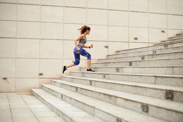 sportive woman running up stairs outdoors  - Foto, afbeelding