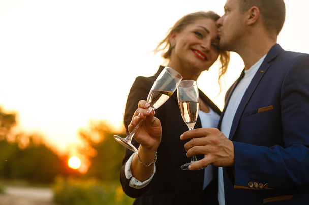 Молода пара святкує з шампанським на заході сонця
 - Фото, зображення