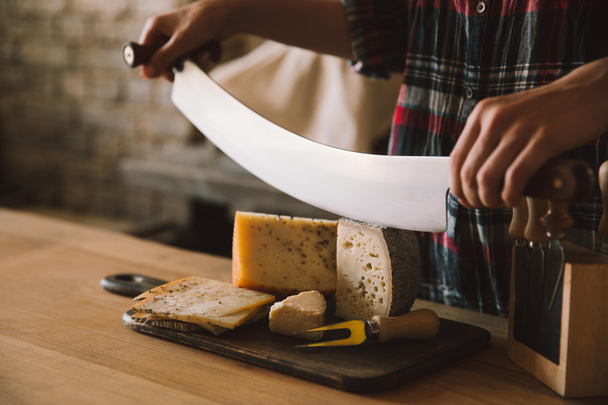 Colpo ritagliato di donna che taglia delizioso formaggio con doppio coltello maneggiato
 - Foto, immagini