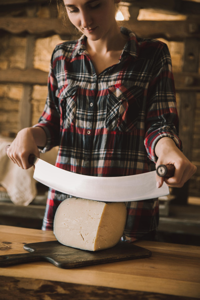 junge Frau schneidet mit doppeltem Messer Käse - Foto, Bild