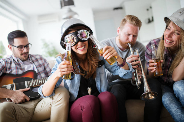 Group of happy friends playing guitar and partying at home - Фото, изображение
