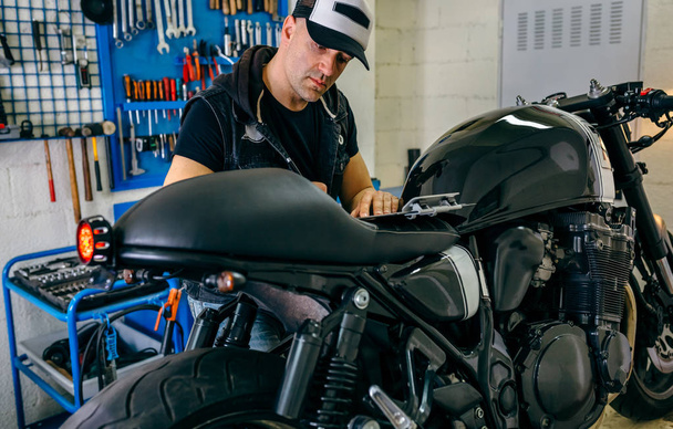 Mechaniker überprüft Motorrad und macht sich Notizen - Foto, Bild