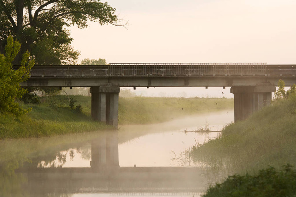 Γέφυρα πάνω από τον ποταμό στην πρωινή ομίχλη, καλοκαίρι - Φωτογραφία, εικόνα