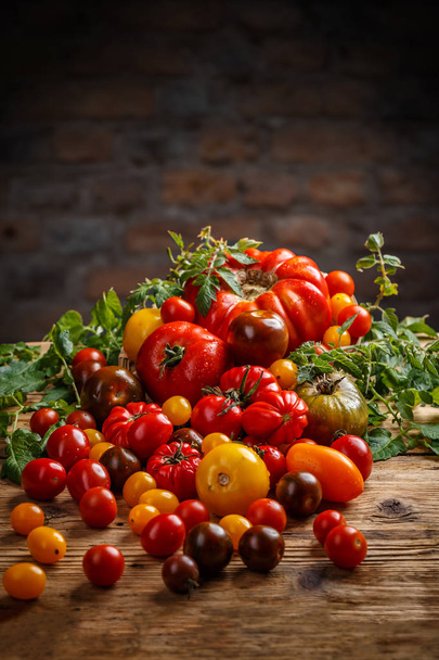 Healthy colorful tomatoes on old wooden background - Valokuva, kuva