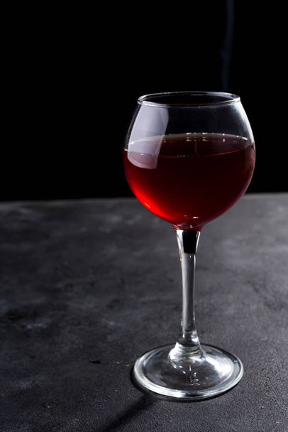 Red wine glass with beautiful long shadows on stone table. With copy space for your text - Фото, изображение