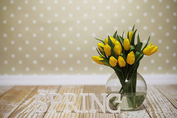 Kukkakimppu keltaisia tulppaaneja maljakossa lattialla. Lahja w: lle
 - Valokuva, kuva