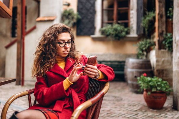 Pretty girl with curly hair using phone outdoor - 写真・画像