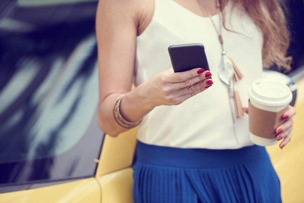 abgeschnittenes Bild einer Frau, die im Smartphone surft und Kaffeebecher in der Hand hält  - Foto, Bild