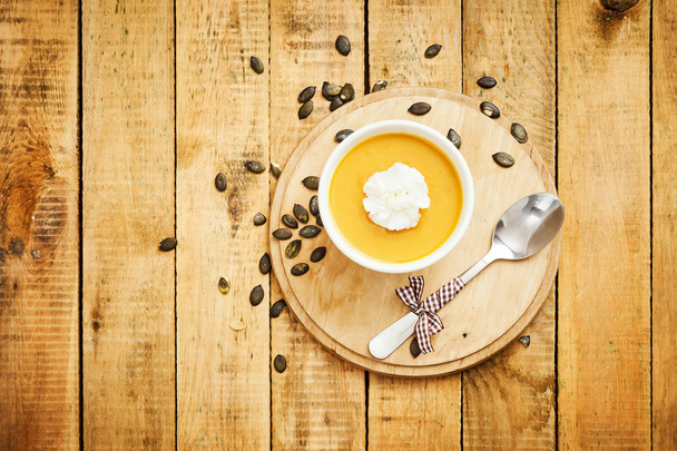 fresh and delicious pumpkin soup on an old wooden kitchen table - Фото, изображение
