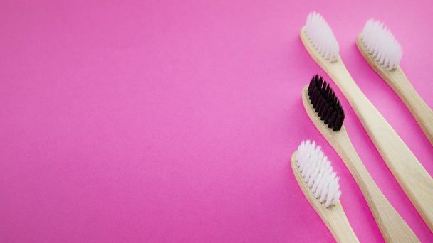 Μαύρο και άσπρο ξύλινες μπαμπού οδοντόβουρτσες σε ροζ φόντο. Έννοια του ρατσισμού, κοινωνικός αποκλεισμός, κατάθλιψη ή μοναξιά, κοινωνικά προβλήματα ή παράνομης μετανάστευσης - Φωτογραφία, εικόνα