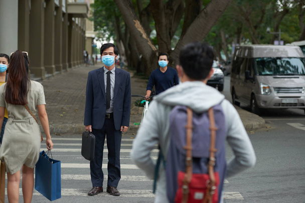 Азиаты в масках переходят дорогу в городе
  - Фото, изображение