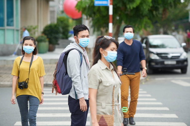 Aziatische stad bewoners wandelen buiten in gezichtsmaskers vanwege de luchtvervuiling - Foto, afbeelding