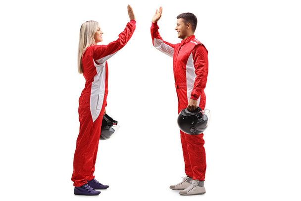 Full length profile shot of a female and a male racer high-fiving each other isolated on white background - 写真・画像