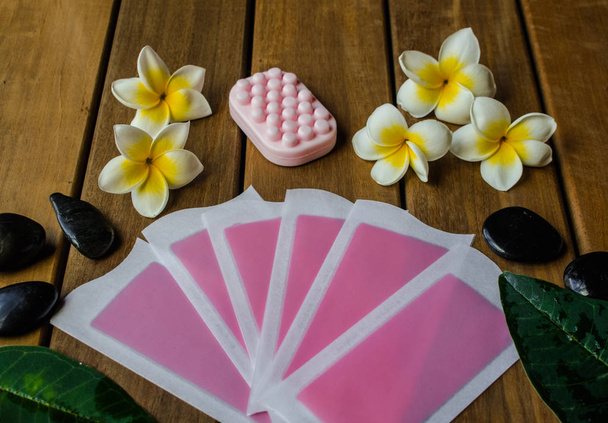Růžový studeným voskem pásy s růžové mýdlo na dřevěné ploše s květy plumeria a Černé kulaté kameny - Fotografie, Obrázek