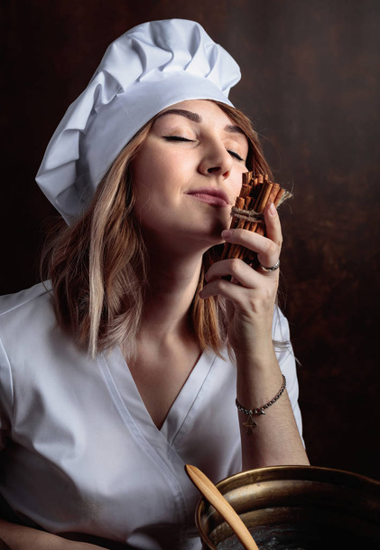  Krásná mladá dívka v uniformě kuchař se skořicí hole. - Fotografie, Obrázek