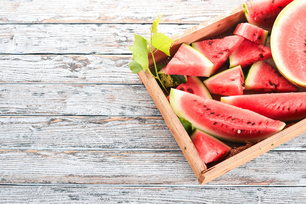 Watermelon in a wooden box. Sliced to pieces of watermelon. On a wooden background. Free space for text. Top view. - Fotó, kép