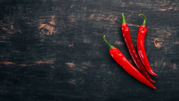 Chili red pepper. On a black wooden background. Free space for text. Top view. - Foto, Imagen