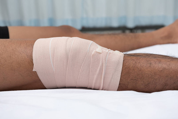 Les physiothérapeutes utilisent les poignées de la jambe du patient pour s'allonger sur le lit dans une salle médicale.
. - Photo, image