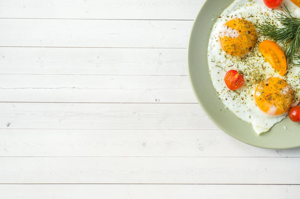 Fried eggs with cherry tomatoes on a plate. - Фото, зображення