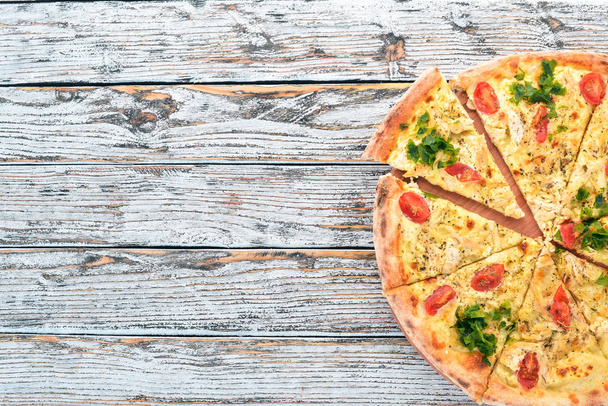 Pizza with cherry tomatoes, suluguni cheese and basil. Italian cuisine. On a wooden background. Free space for text. Top view. - Foto, immagini