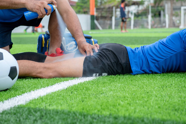 Fotbalista na sobě modrou košili, černé kalhoty, zraněn v trávníku během závodu. - Fotografie, Obrázek