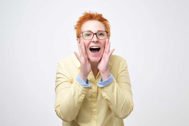 Do not tell anyone concept. Talkative prettyeuropean woman with red hair is saying secret hot braking news isolated on grey background - Foto, imagen