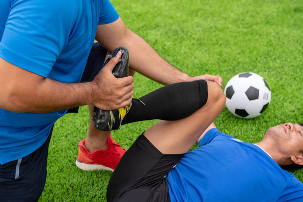 Footballer wearing a blue shirt, black pants injured in the lawn during the race. - Fotó, kép