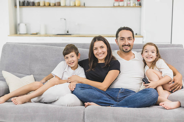 Happy family of four sitting on sofa. Happy family. Father, mother and children at home - Foto, afbeelding