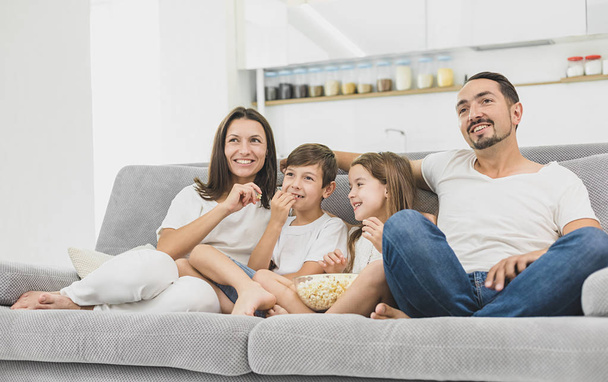 Young family watching TV together at home and having fun together - Foto, Imagen