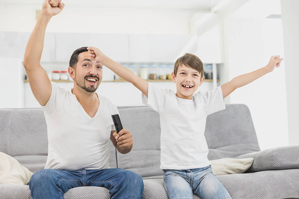 Real fun. Positive aged father and son watching football at home - Фото, изображение