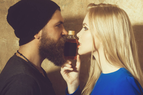Hipster and girl posing with bottle of liqueur - Φωτογραφία, εικόνα