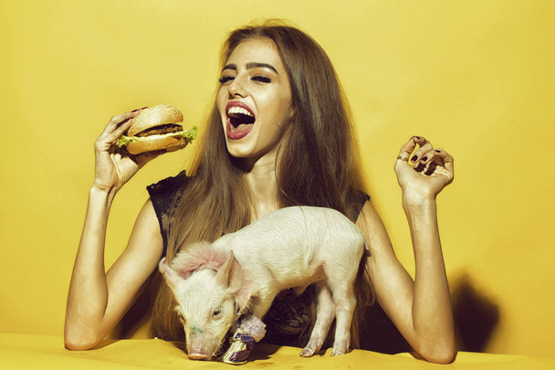 Girl eating burger with pig - Foto, afbeelding
