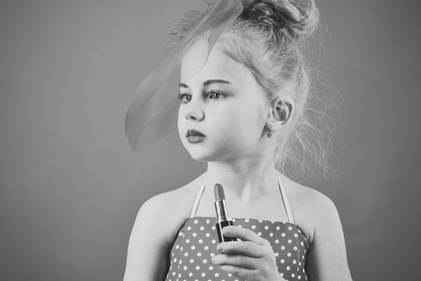 Retro girl fashion with cosmetics, beauty. Little girl hold lipstick and mirror. Fashion and beauty, pinup style, childhood. Child girl in stylish dress, makeup. Makeup retro look and hairdresser. - Photo, image