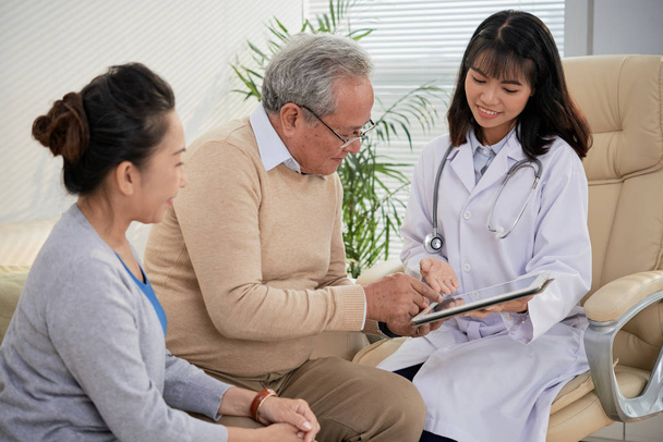 Lächelnder Arzt zeigt älteren Patienten medizinische Testergebnisse - Foto, Bild