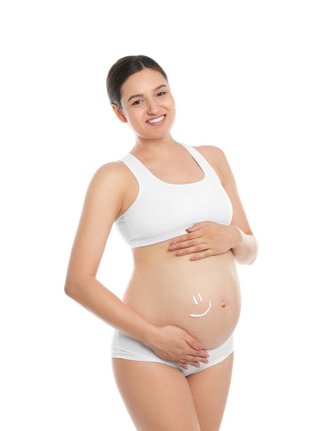 Pregnant woman with smile painted on her belly against white background. Body cream - Foto, afbeelding