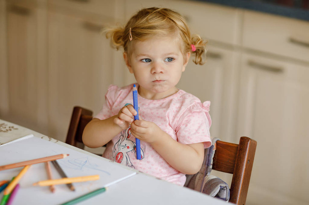 Niedliche entzückende Baby Mädchen lernen Malerei mit Bleistiften. Kleines Kleinkind zeichnet zu Hause mit bunten Filzstiften. Gesunde glückliche Tochter experimentiert zu Hause oder im Kinderzimmer mit Farben. - Foto, Bild