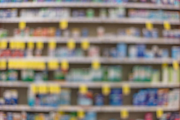 Blurred abstract background inside pharmacy store with arranged variation of pharmaceutical and medical supplies product in label on shelves display. Indoor drug store with blurred medicines. Panorama - Photo, Image