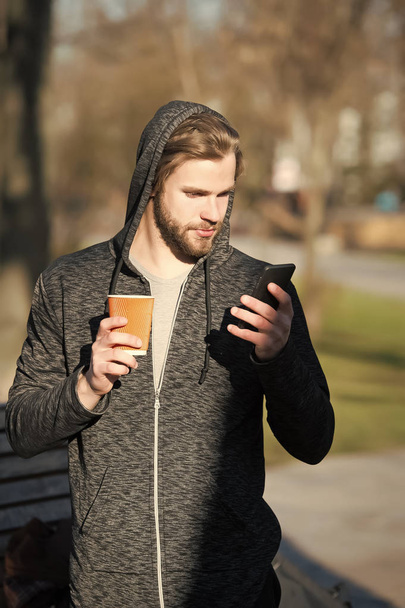 young man holds coffee, tea paper cup, phone in jersey - Foto, Imagem