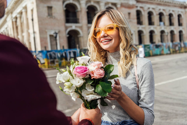 cropped image of boyfriend presenting bouquet of roses to girlfriend on street in city - Φωτογραφία, εικόνα